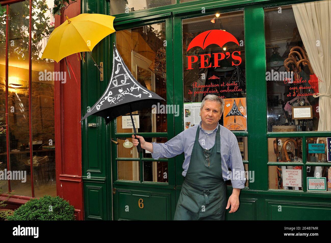 Thierry Millet, l'ultimo riparatore di ombrelli della Francia, pone con la  sua ultima invenzione, un ombrello 'Torre Eiffel' fuori dalla sua officina  'PEP'S, in le Passage de l'Ancre, terzo arrondissement di Parigi,