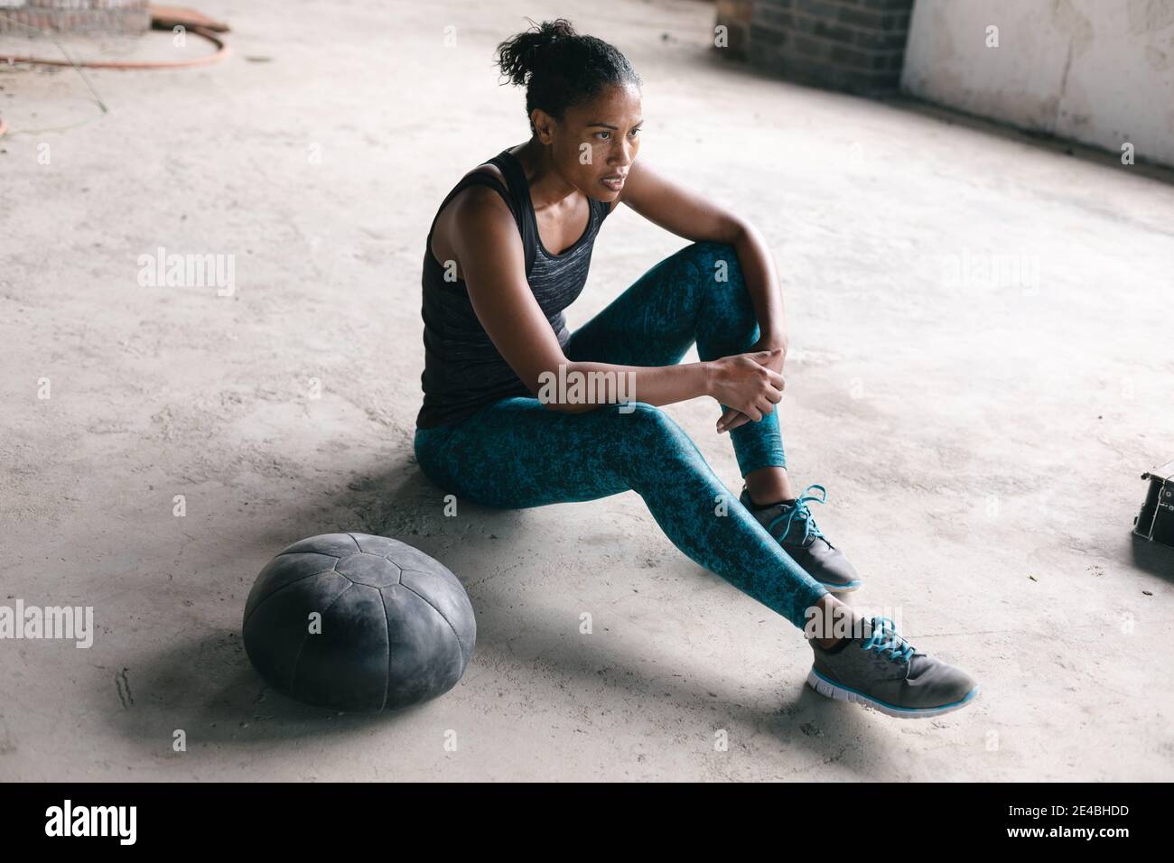 Donna afroamericana seduta da una palla di medicina in vuoto edificio urbano Foto Stock