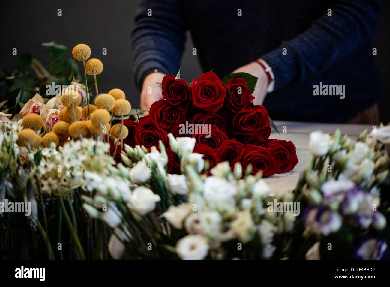 Fiorista caucasico che vende bouquet di rose rosse e rosa per la giornata di San Valentino. Concetto di emozioni umane, espressione facciale, amore e duro lavoro Foto Stock