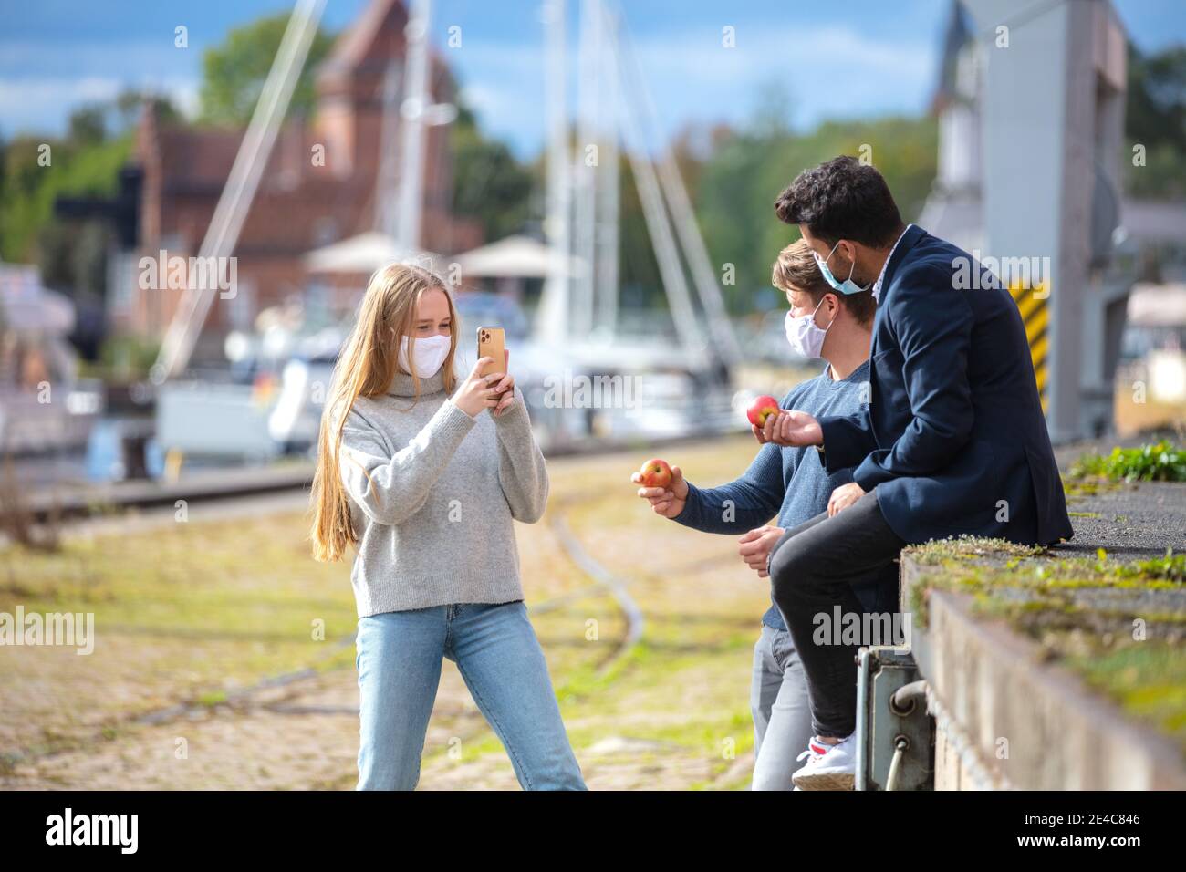 Due uomini e una donna nel tempo di Corona, con maschere quotidiane, fuori e circa in città. Tempo libero con maschera all'aperto. Foto Stock