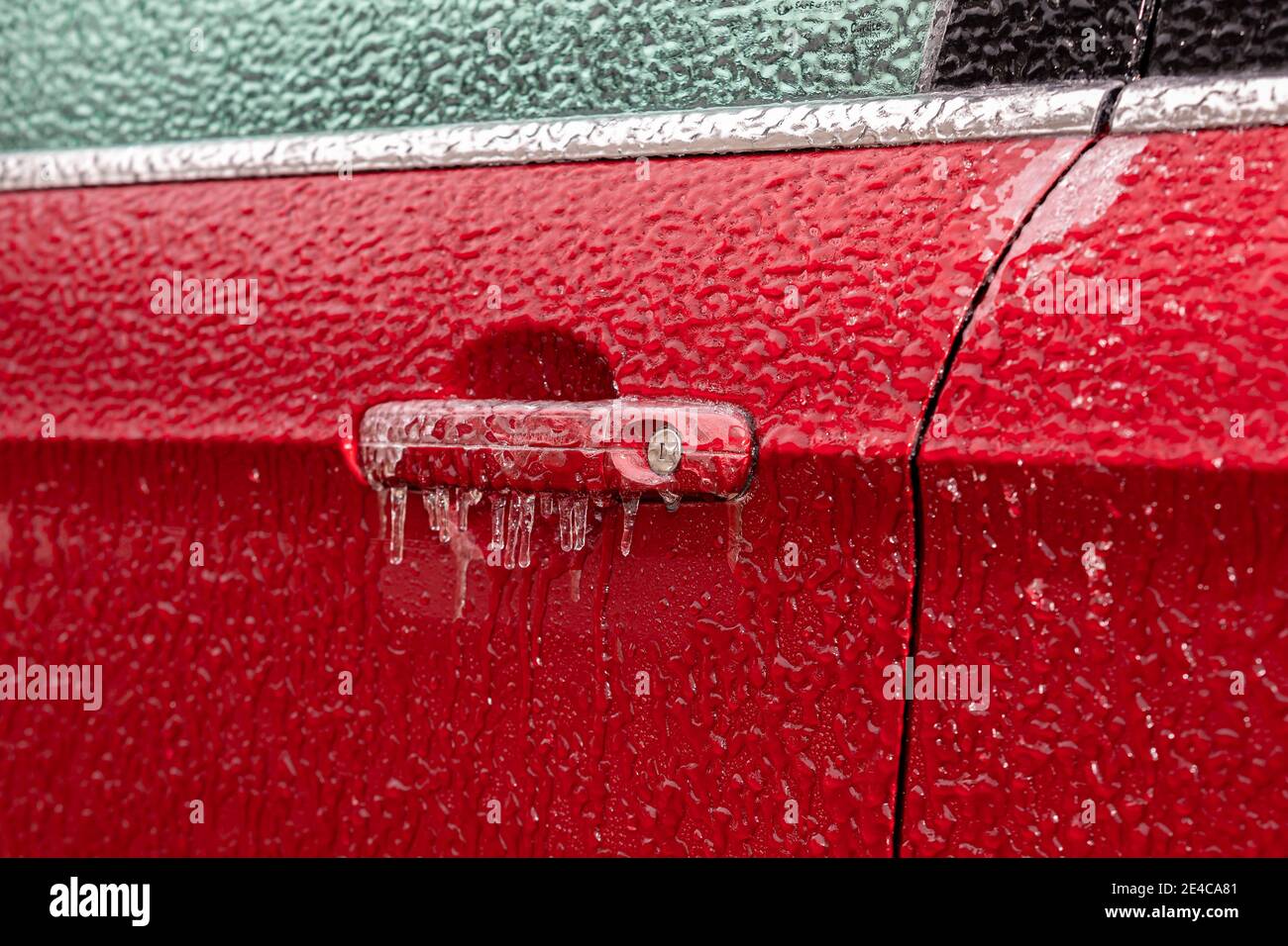 Chiusura della maniglia della porta dell'auto e della serratura ricoperta di ghiaccio durante la tempesta invernale. Concetto di preparazione e sicurezza alla guida invernale Foto Stock