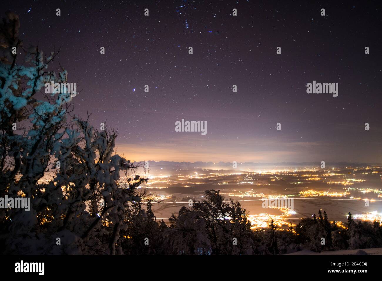 Spirito di Natale, fresco neve-coperto paesaggio sotto il cielo stellato, luci nella valle Foto Stock
