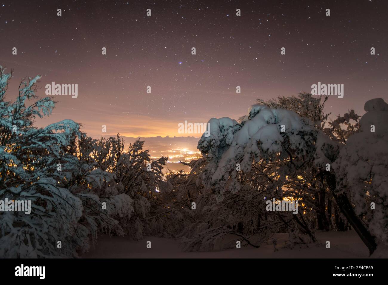 Spirito di Natale, fresco neve-coperto paesaggio sotto il cielo stellato, luci nella valle Foto Stock