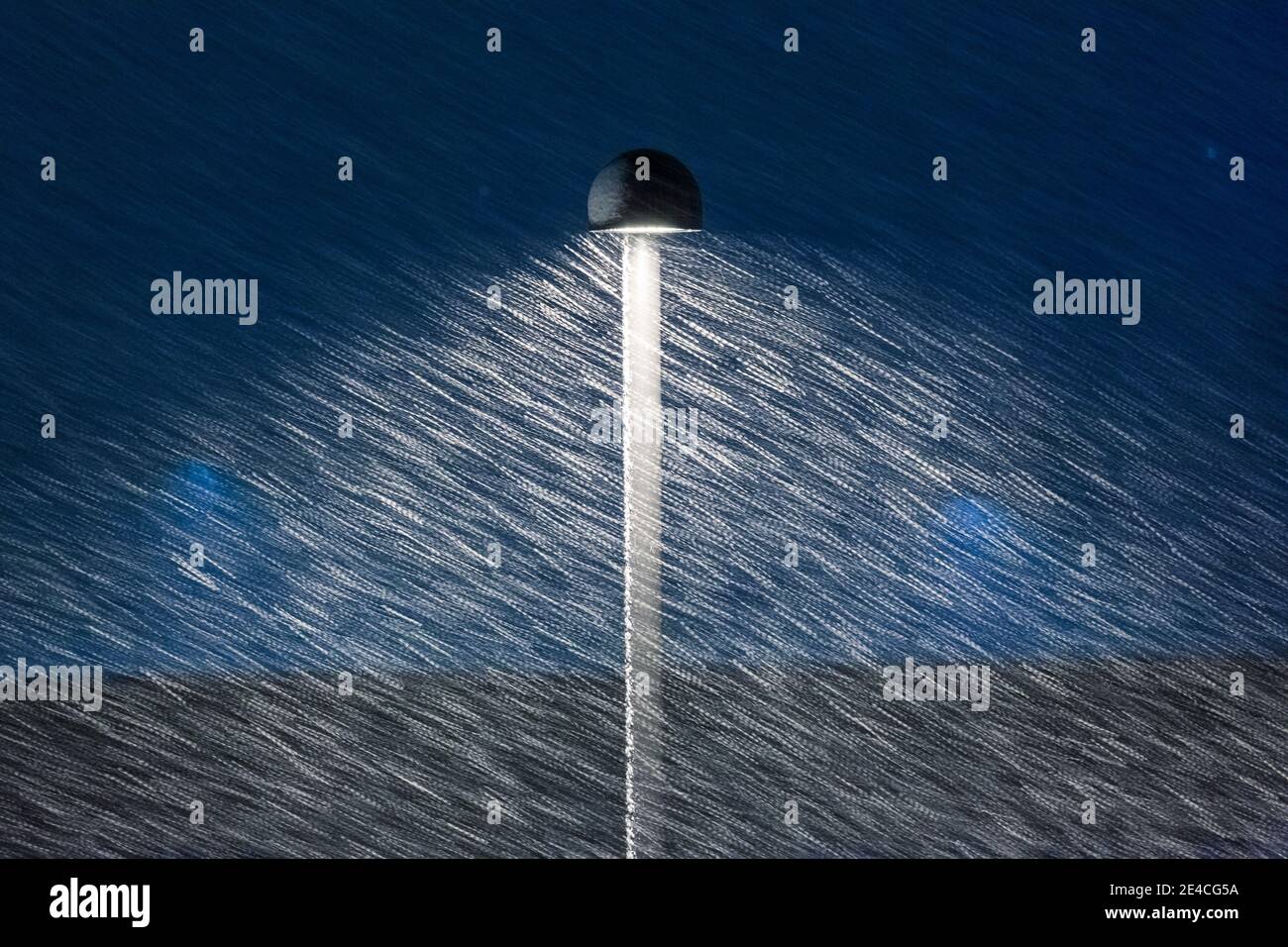 scena urbana invernale, la lampada da strada illumina la notte sotto una bizzarda Foto Stock