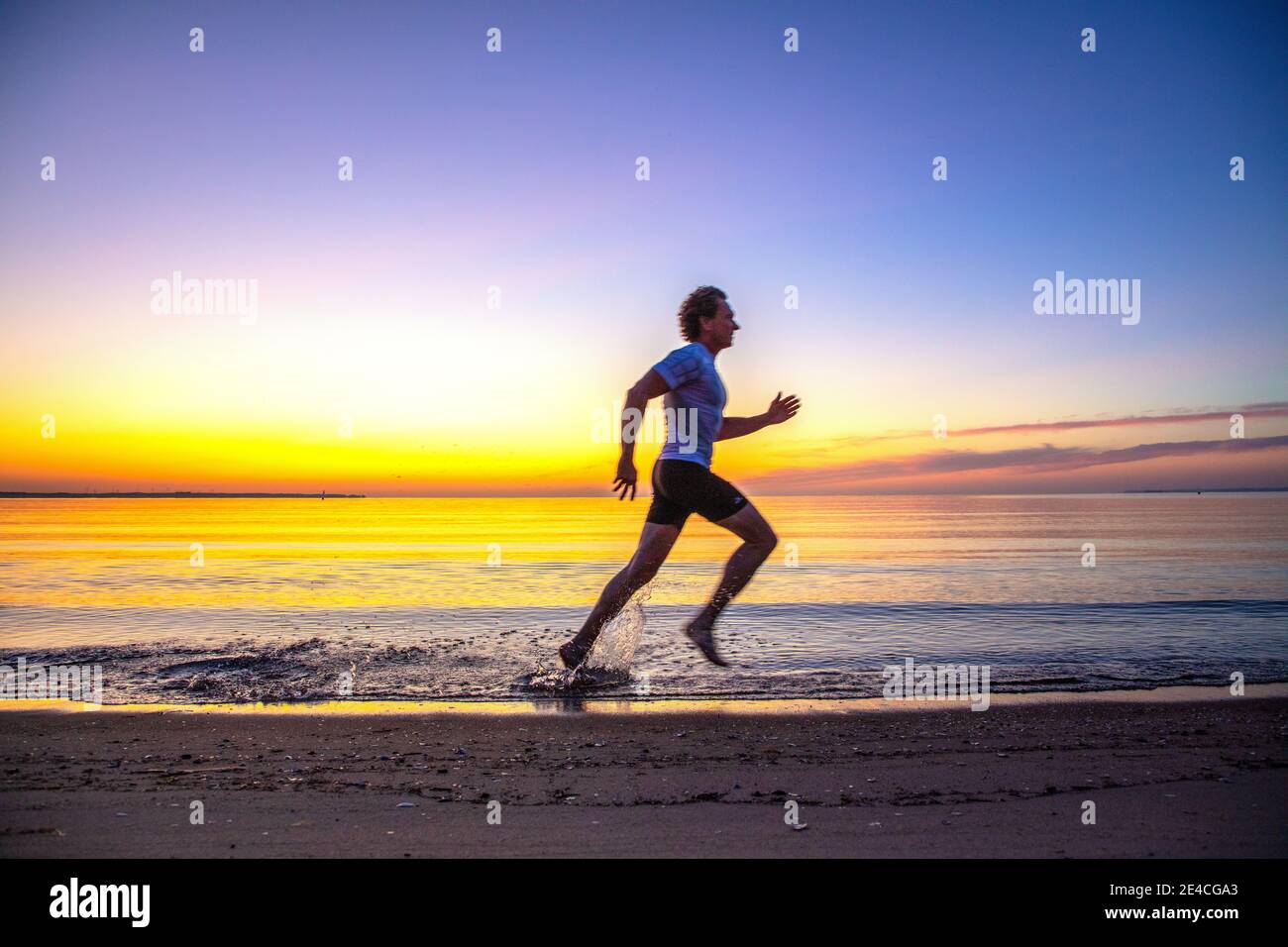 Man 50 Plus fit, sport all'alba sul mare. Corsa sulla spiaggia di Scharbeutz. Foto Stock