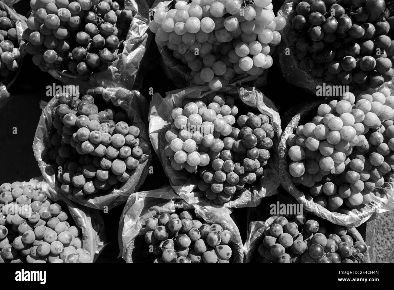 Gruppo di belle uve bianche e rosse/viola/nere, tutte collocate in un mercato dai colori vivaci e dall'aspetto sano. Foto Stock