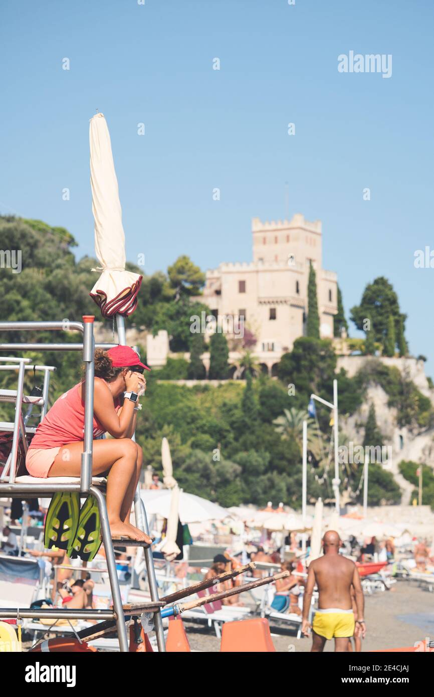 Bagnino in spiaggia seduto in servizio. Italia, finale ligure - 23 agosto 2020. Foto Stock