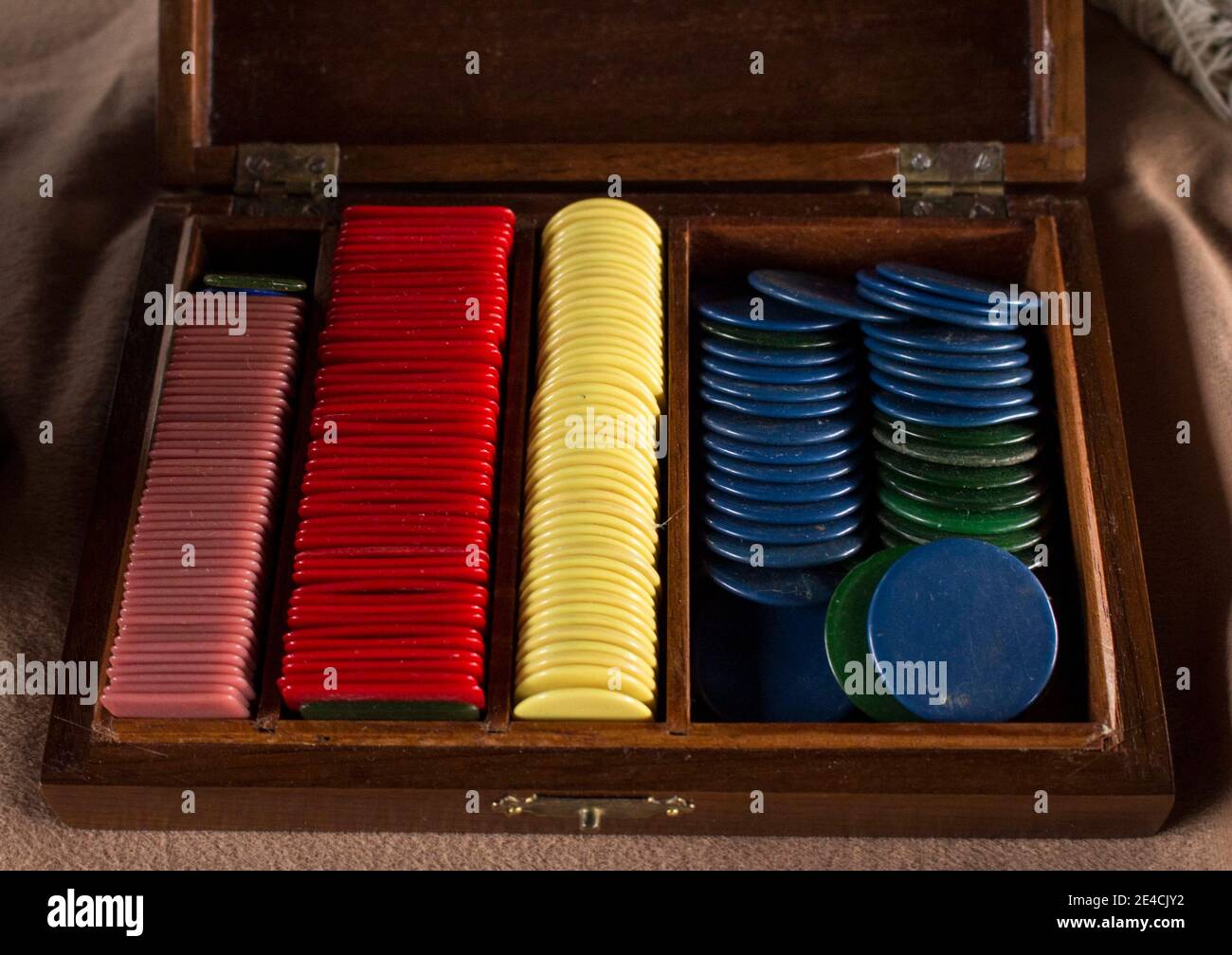 Multiple chip di plastica da poker (o utilizzati per un altro gioco) all'interno di bella vecchia scatola di legno artigianale. Diversi colori di chip impilati tutti insieme Foto Stock
