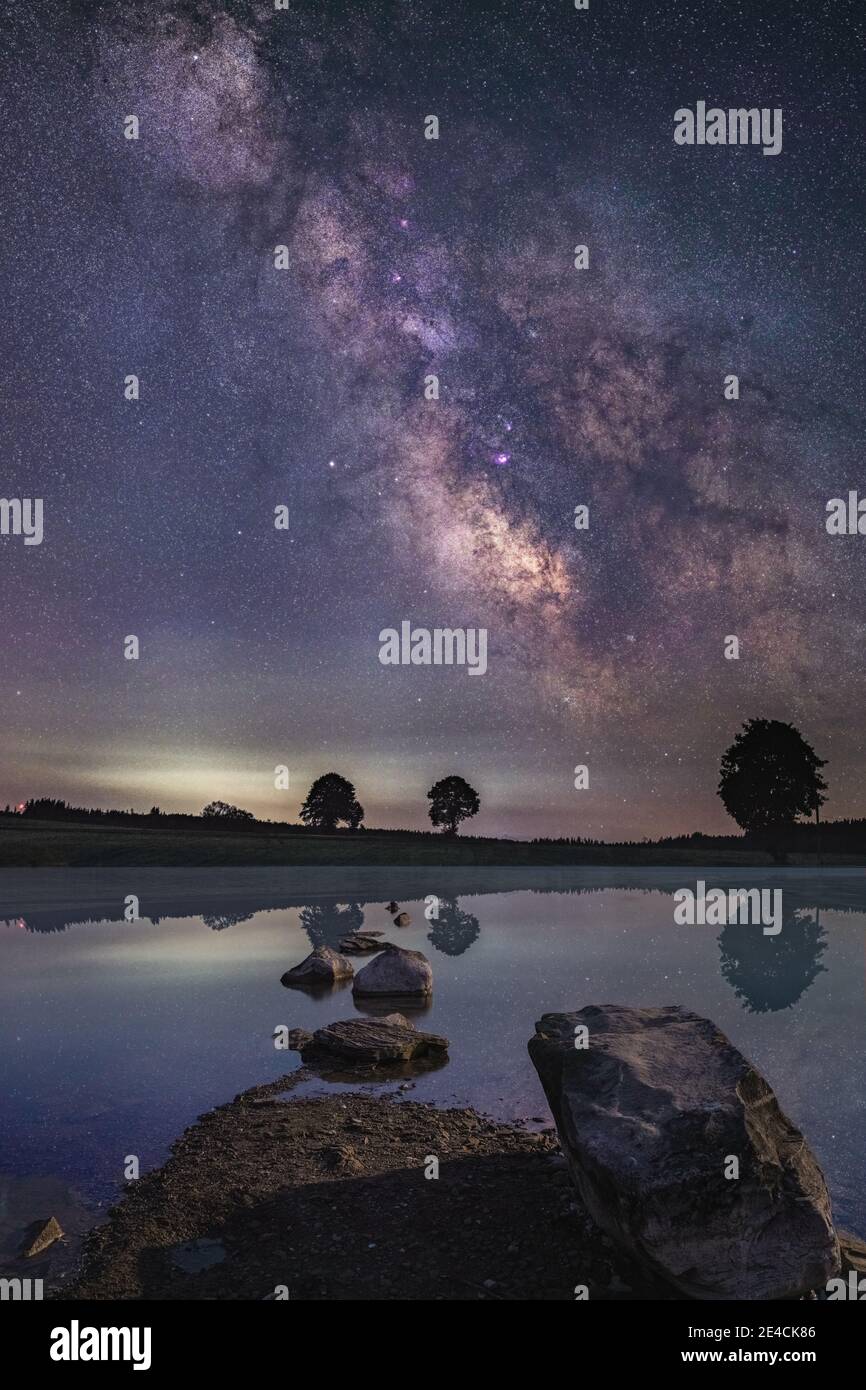 Composizione di un paesaggio da sogno con un lago di Allgäu in primo piano e una Via Lattea su un altopiano di Allgäu. Foto Stock