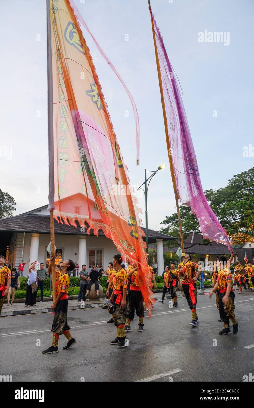 Giovani uomini con bandiere alte a New Years sfilano a Kuching, Malesia Foto Stock