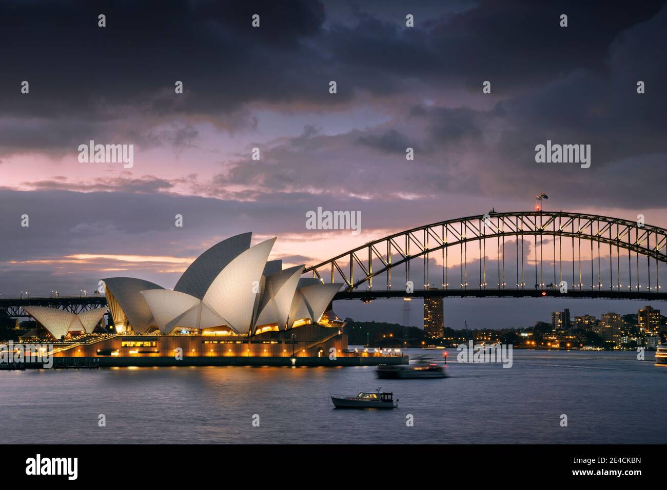 La Sydney Opera House illuminata con Harbour Bridge al tramonto Foto Stock