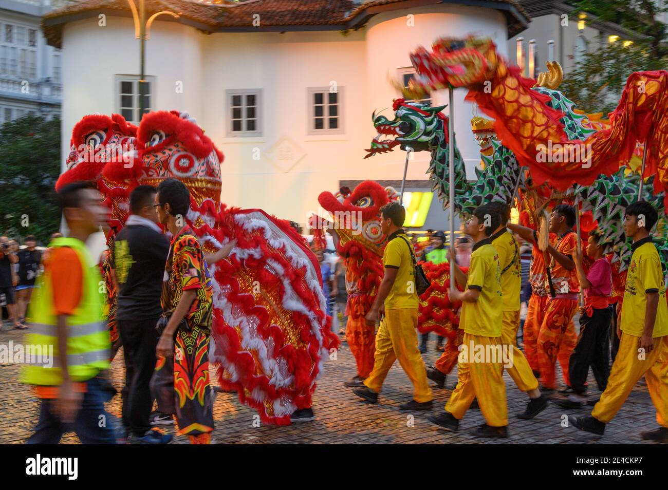 Giovani uomini che marciano con i draghi nella sfilata cinese di Capodanno a Kuching, Malesia Foto Stock