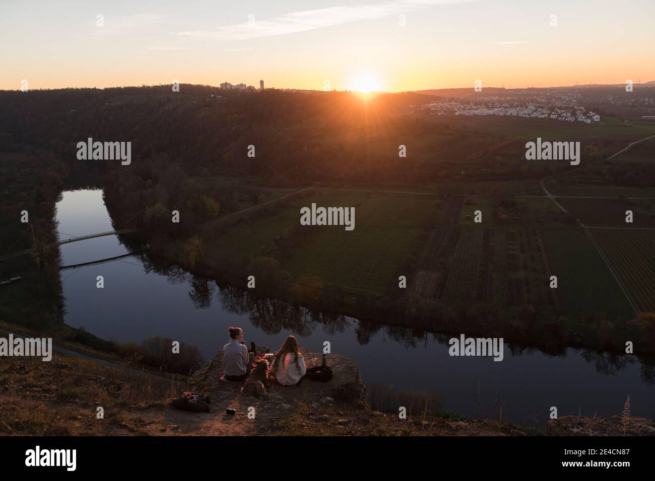 Europa, Germania, Baden-Wuerttemberg, Besigheim, Hessigheim, due giovani donne che hanno un pic-nic sulle rocce nei giardini rocciosi sopra il Neckar al tramonto Foto Stock