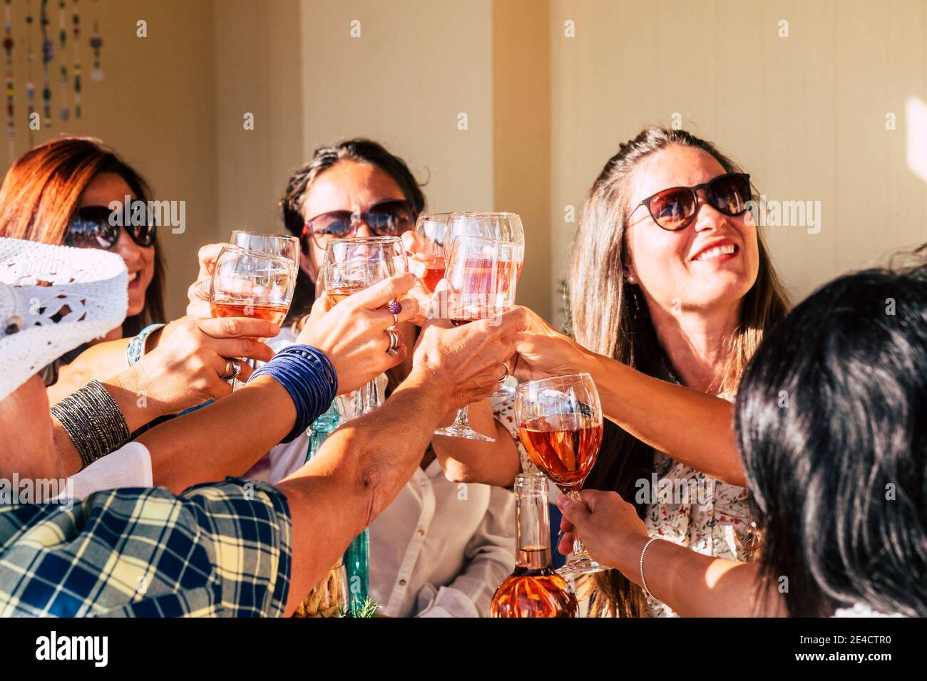 Gruppo di allegre giovani donne caucasiche che si divertono e festeggiano insieme unire i bicchieri di vino rosso: la gente si diverte celebrazione con bevande e cibo sul tavolo Foto Stock