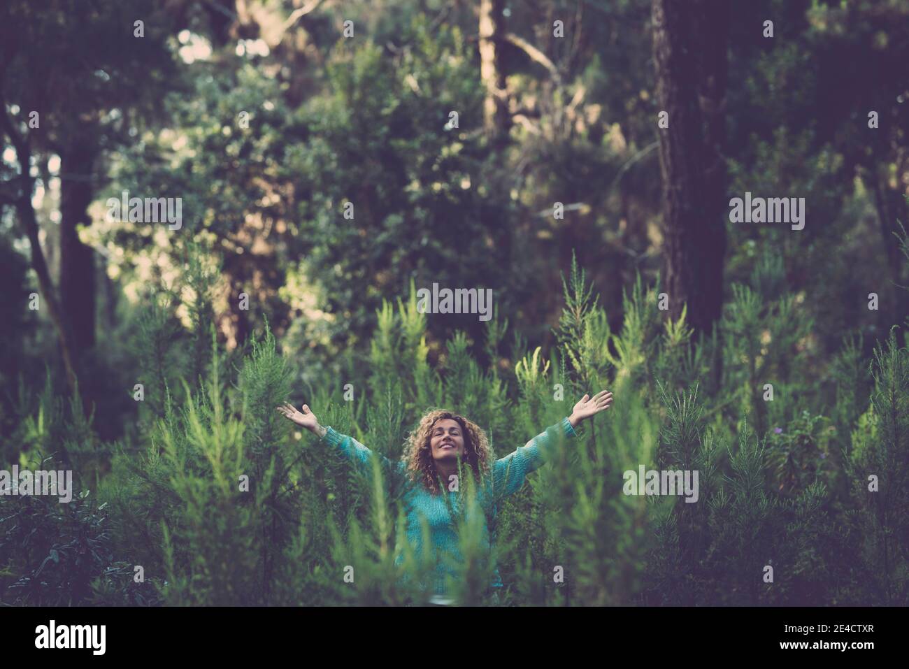 Abbracciando outdoor e amore natura concetto con felice bella donna nel mezzo di un bosco di alberi in totale felicità e gioia - celebrazione del giorno della terra per salvare il pianeta Foto Stock