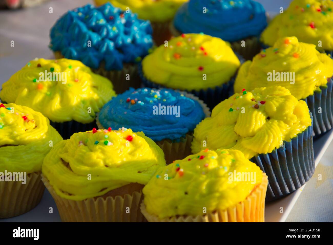 Cupcake fatti in casa colorati blu e gialli con spruzzi, minion Concept party, dessert in blu e giallo su un tavolo Foto Stock