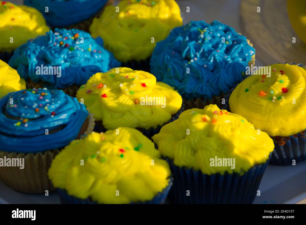 Cupcake fatti in casa colorati blu e gialli con spruzzi, minion Concept party, dessert in blu e giallo su un tavolo Foto Stock