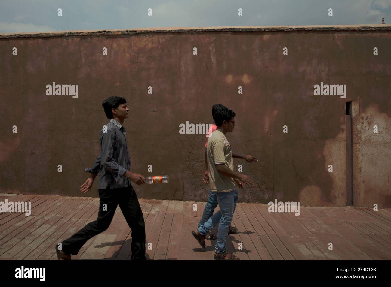 Un gruppo di giovani uomini che camminano lungo la passerella all'interno del Forte di Agra in una giornata di sole ad Agra, Uttar Pradesh, India. Foto Stock