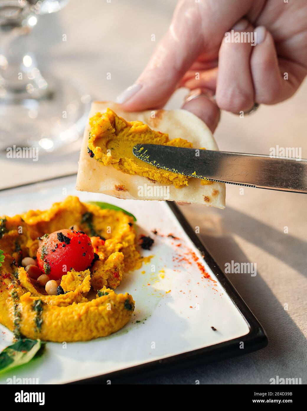 Spalmare l'ummus curry su pita con un coltello Foto Stock