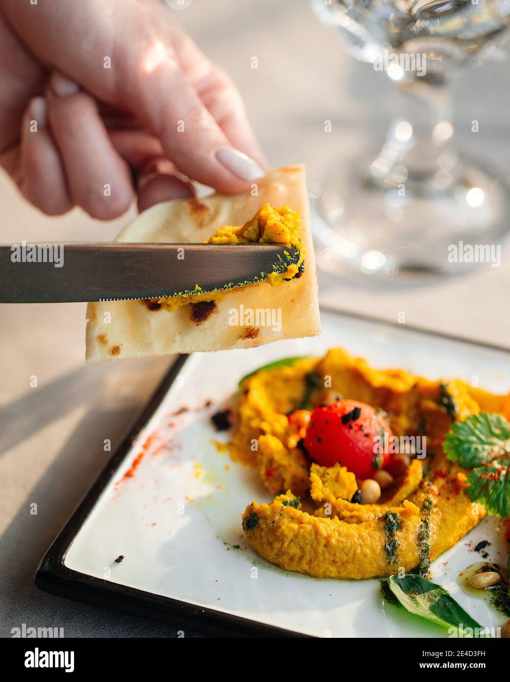 Spalmare l'ummus curry su pita con un coltello Foto Stock