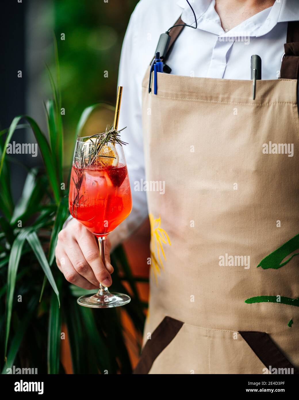 Cameriere che tiene un bicchiere di aperol Spritz cocktail con un paglia Foto Stock