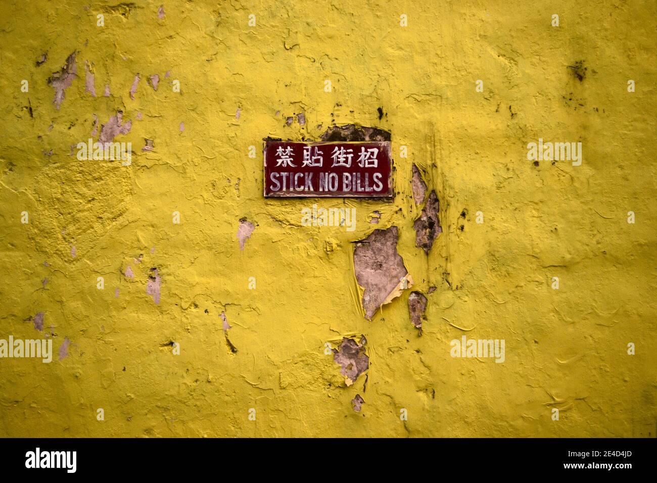 Vecchio muro di grunge giallo con con avviso bastone senza bollette In inglese e cinese Foto Stock