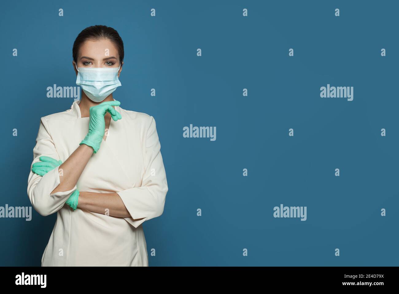 Medico in maschera medica protettiva e guanti chirurgici in nitrile su sfondo blu, medicina, sicurezza e protezione antivirus concetto Foto Stock