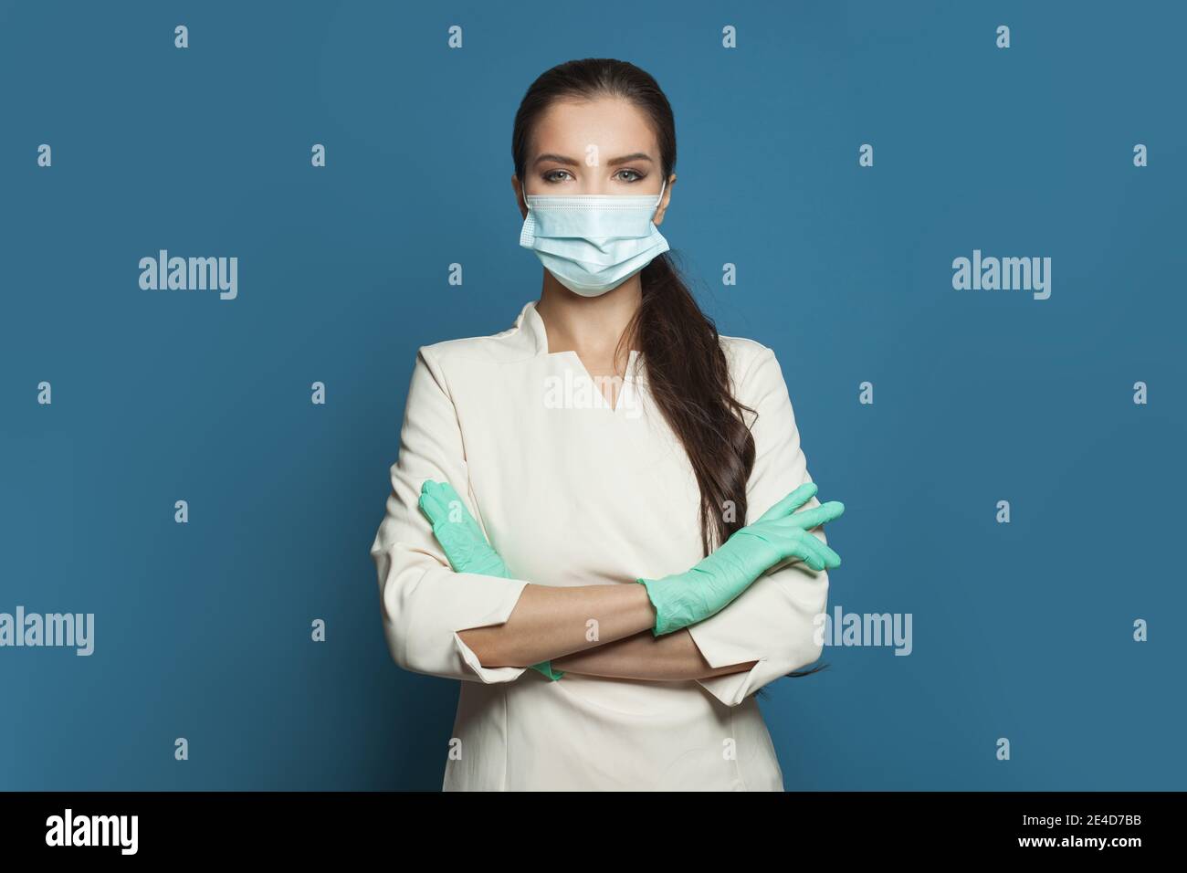 Felice dottore o infermiera in maschera medica protettiva e guanti chirurgici su sfondo blu. Medicina, assistenza, sicurezza e virus covid-19 protec Foto Stock