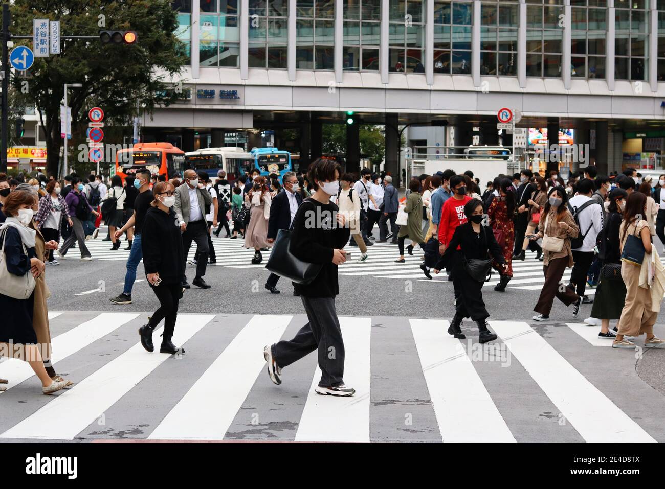 Persone che usano la traversata di scramble di fronte alla stazione di Shibuya. Indossano maschere facciali durante l'epidemia di coronaviurs. Sfocatura del movimento. (10/2020) Foto Stock