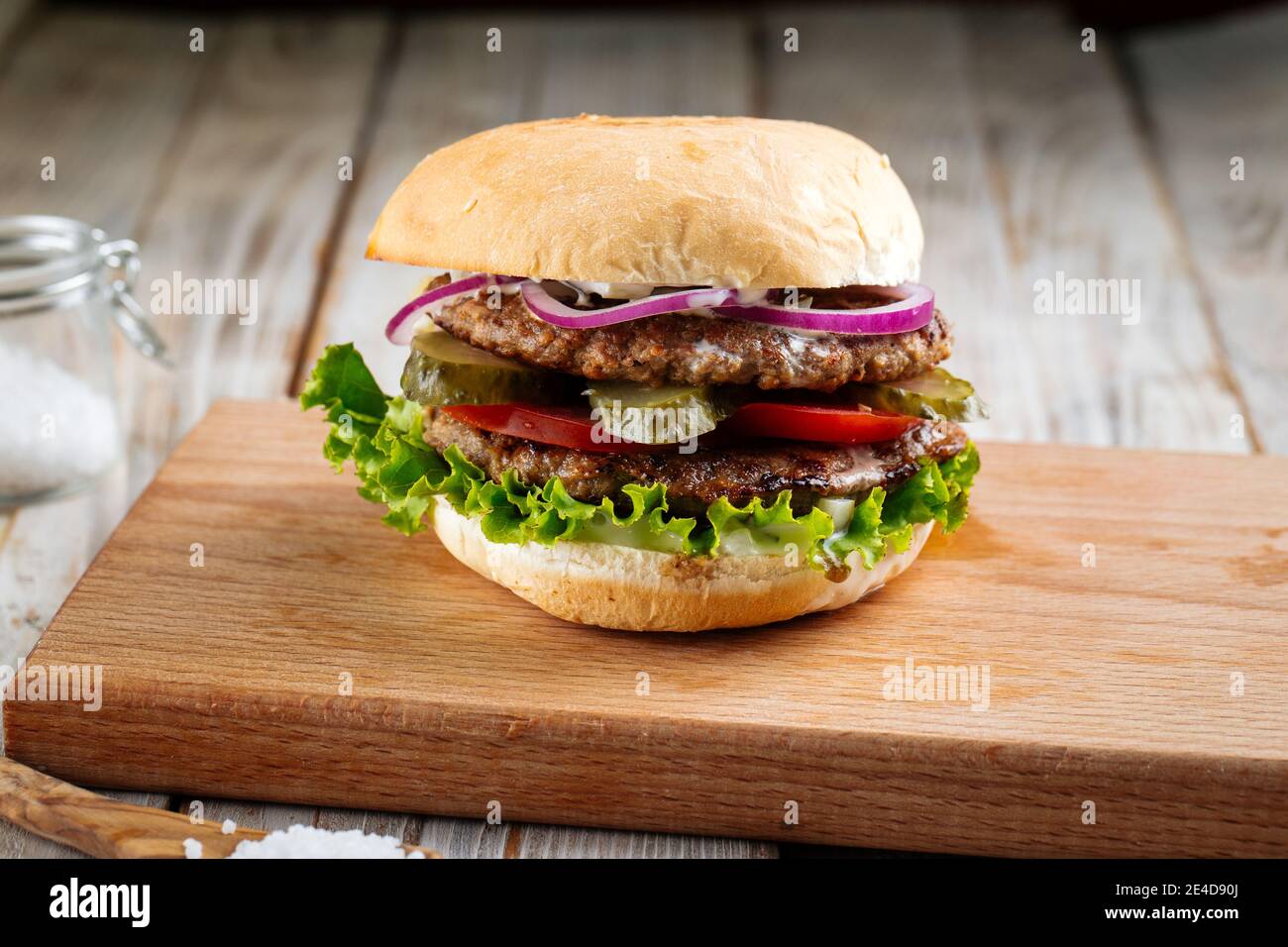 Hamburger doppio patty con sottaceti su tavola di legno Foto Stock