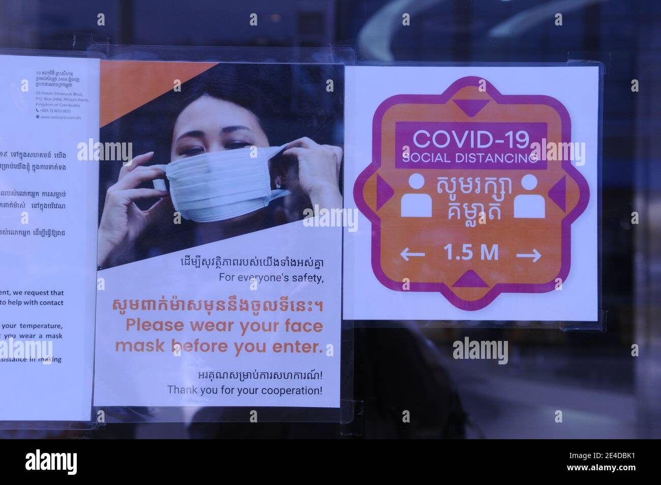 Un COVID bilingue - 19 segnale di avvertimento all'ingresso di un ufficio telefonico durante la pandemia del coronavirus. Phnom Penh, Cambogia. © Kraig Lieb Foto Stock