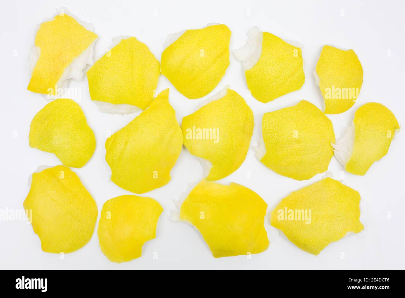 Fondo giallo con pezzi di scorza di agrumi di pomelo su fondo bianco isolato, rifiuti organici brillanti Foto Stock