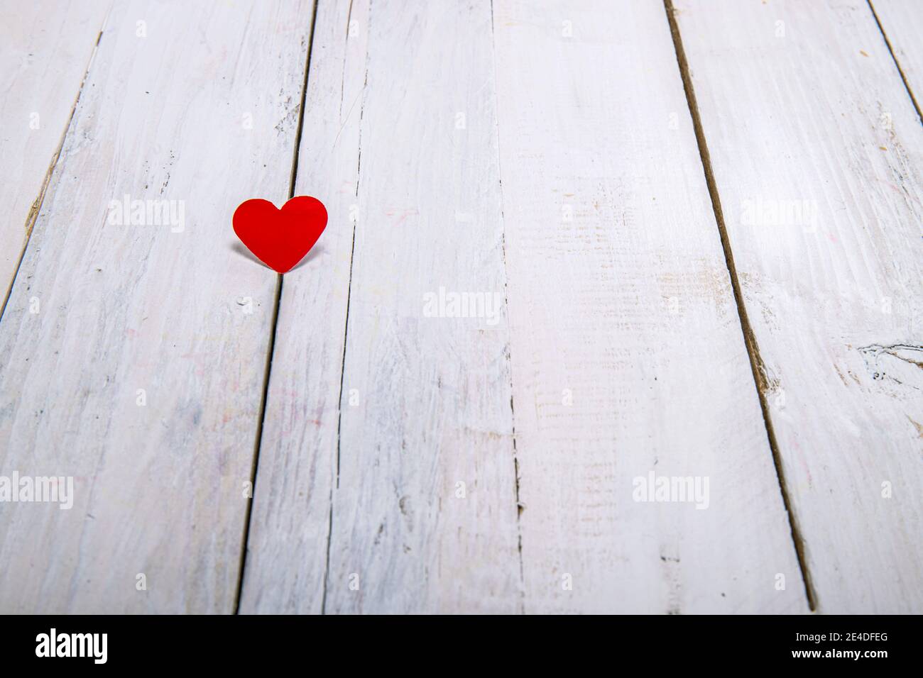 Un piccolo cuore di carta rosso su uno sfondo bianco di legno.per esprimere l'amore con un pensiero semplice e profondo. Foto Stock