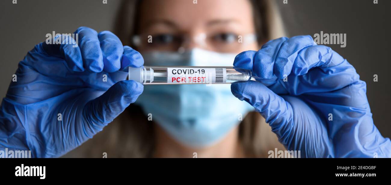 COVID-19 test in primo piano medico mani, donna in maschera medica contiene tubo di test PCR coronavirus in laboratorio. Concetto di test del virus corona, diagn Foto Stock