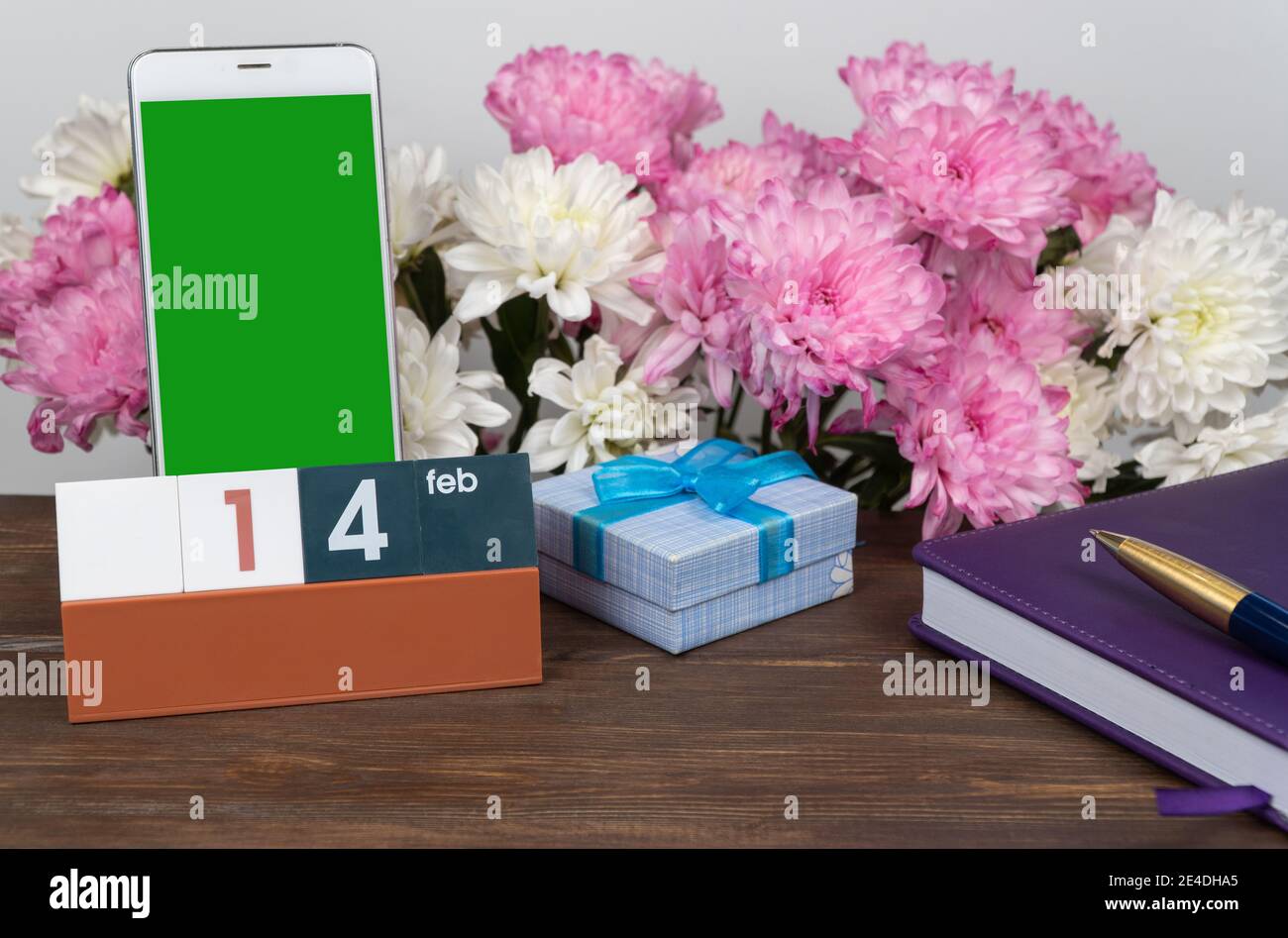 Calendario desktop con data febbraio 14 e un cellulare. Layout per l'inserimento di un'immagine sullo schermo del telefono. Foto Stock