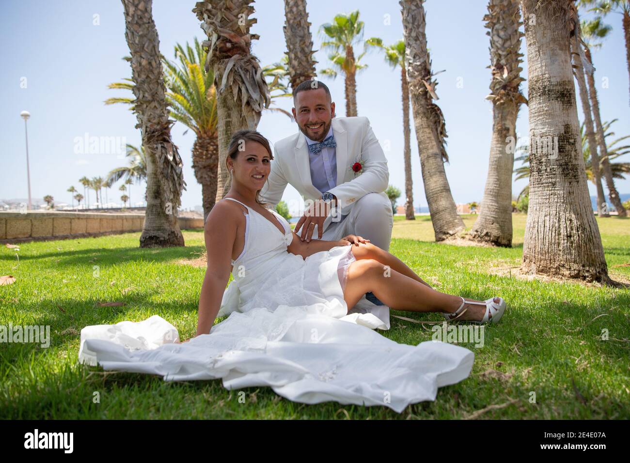 La coppia sposata italiana è felice dopo essersi sposata. Sposa seduta su un campo d'erba accanto allo sposo. Foto Stock