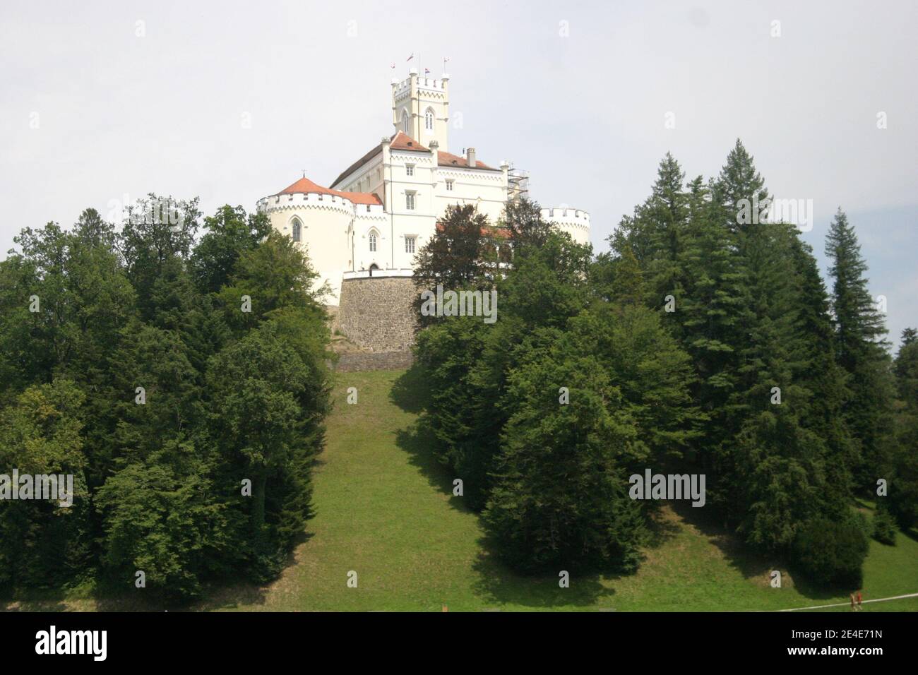 Primo piano di un castello medievale in cima alla collina, circondato da boschi, foto scattata con teleobiettivo, in una giornata parzialmente nuvolosa d'estate Foto Stock