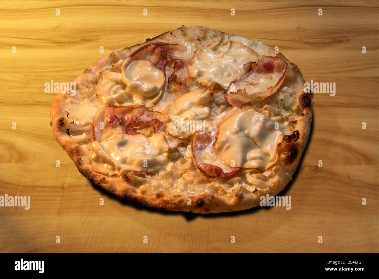 Pizza con formaggio Scamorza, Pancetta di maiale affumicata e cicoria bianca. Luce calda sul tagliere in legno Foto Stock