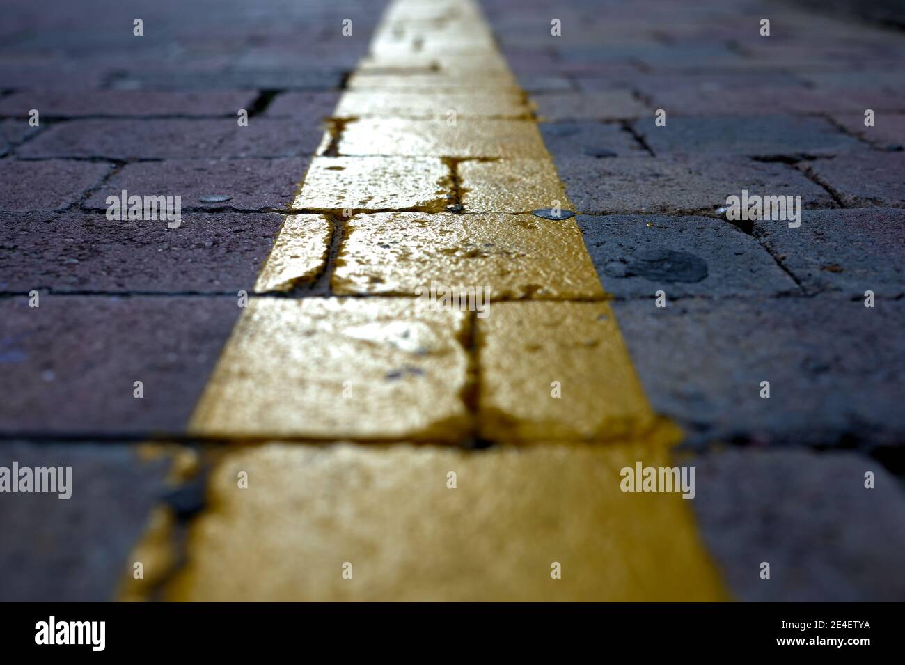 particolare di una linea gialla dipinta su ciottoli come una indicatore di traffico Foto Stock