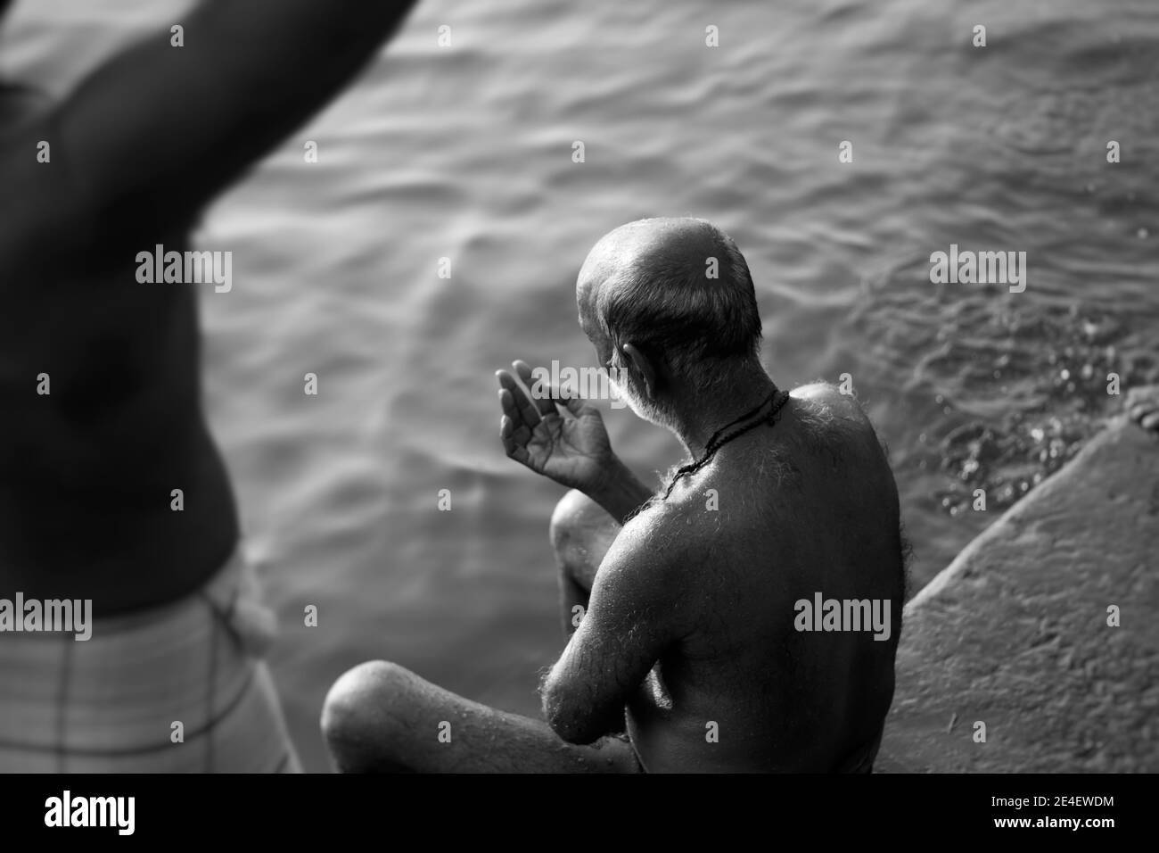 Immagine in scala di grigi di un uomo anziano seduto sulla riva di un lago Foto Stock