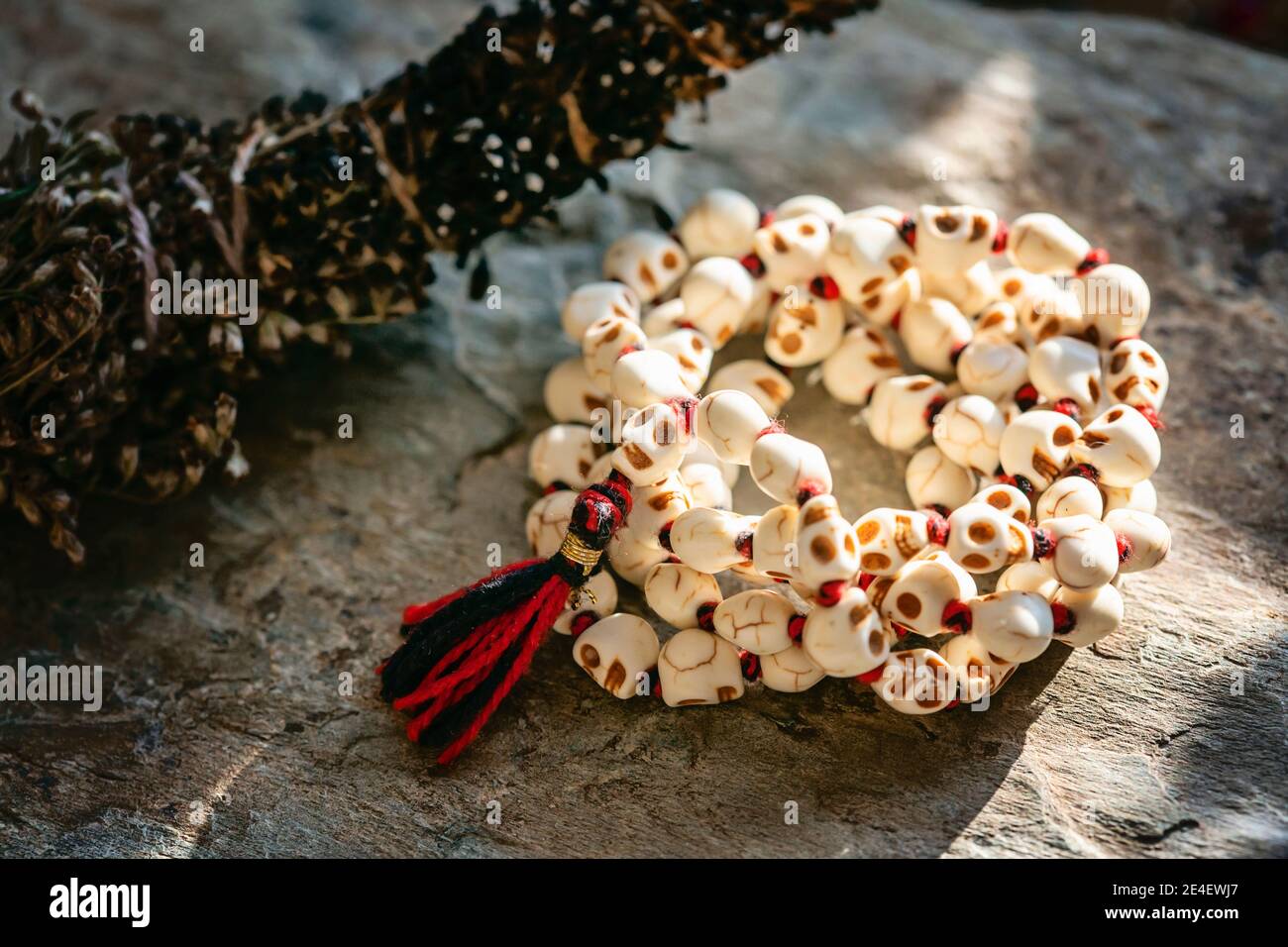 Bianco pietra cranio perline collana mala su sfondo roccioso Foto Stock
