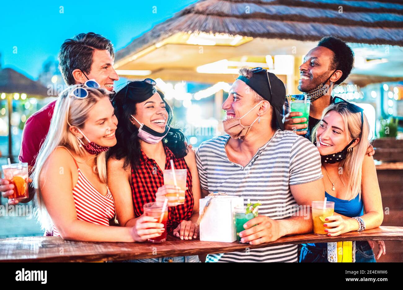Giovani amici internazionali che parlano al cocktail bar sulla spiaggia con aperto Maschera facciale - nuovo concetto di turismo normale con la gente millenaria divertirsi insieme Foto Stock