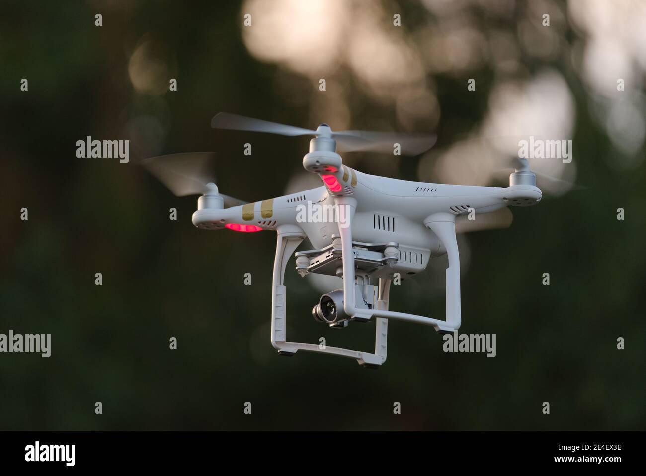 14 - il drone bianco che trasporta una macchina fotografica su un gimbal sembra a sinistra. Ampio spazio di copia grazie alla messa a fuoco selettiva e allo sfondo scuro. Foto Stock