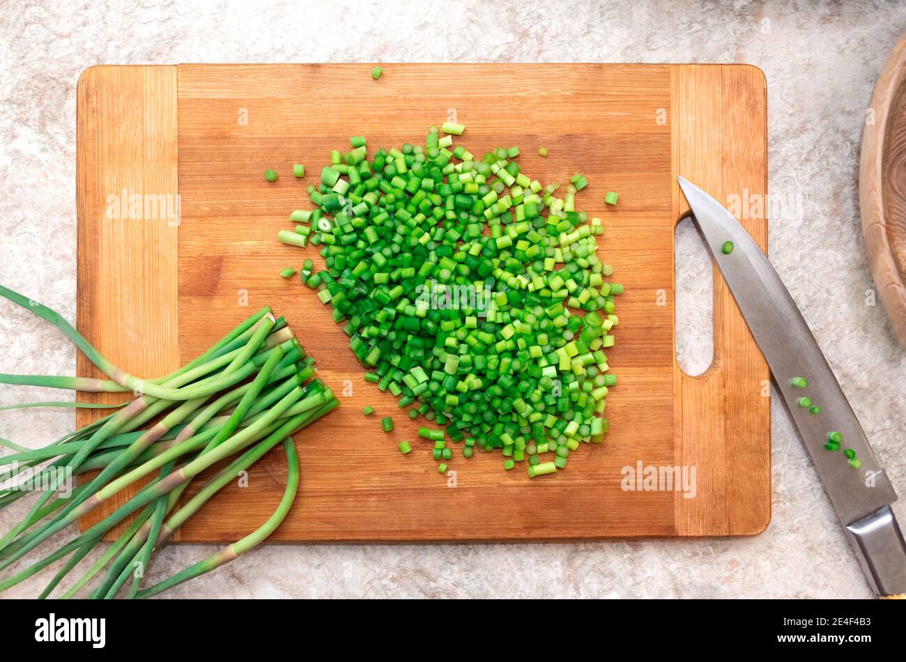 Mazzetto tritato di aglio verde su tagliere di legno con coltello. Cucina. Ingrediente alimentare. Flta Lay Foto Stock