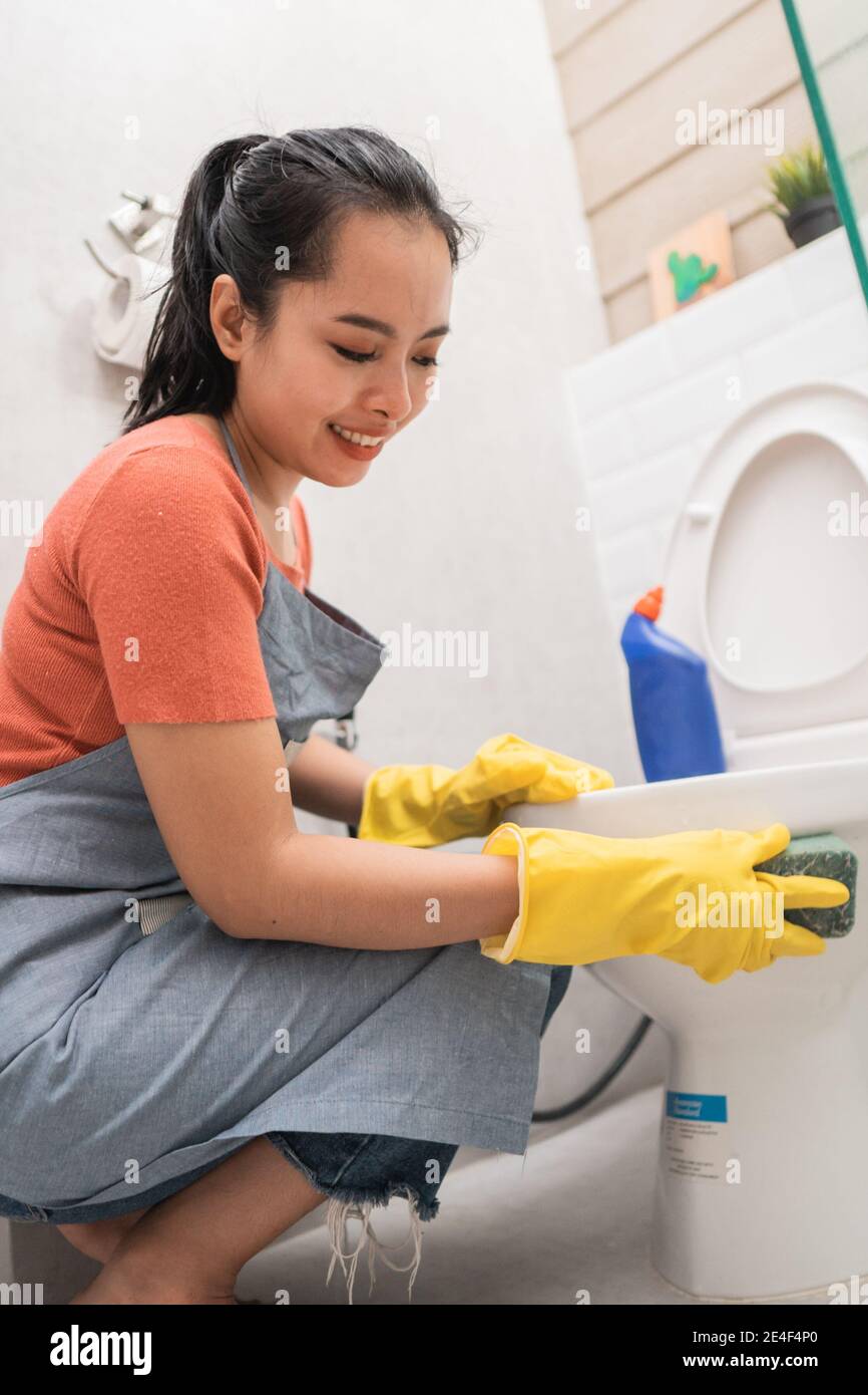 Le donne asiatiche che indossano i guanti puliscono il gabinetto con una  spugna in bagno Foto stock - Alamy