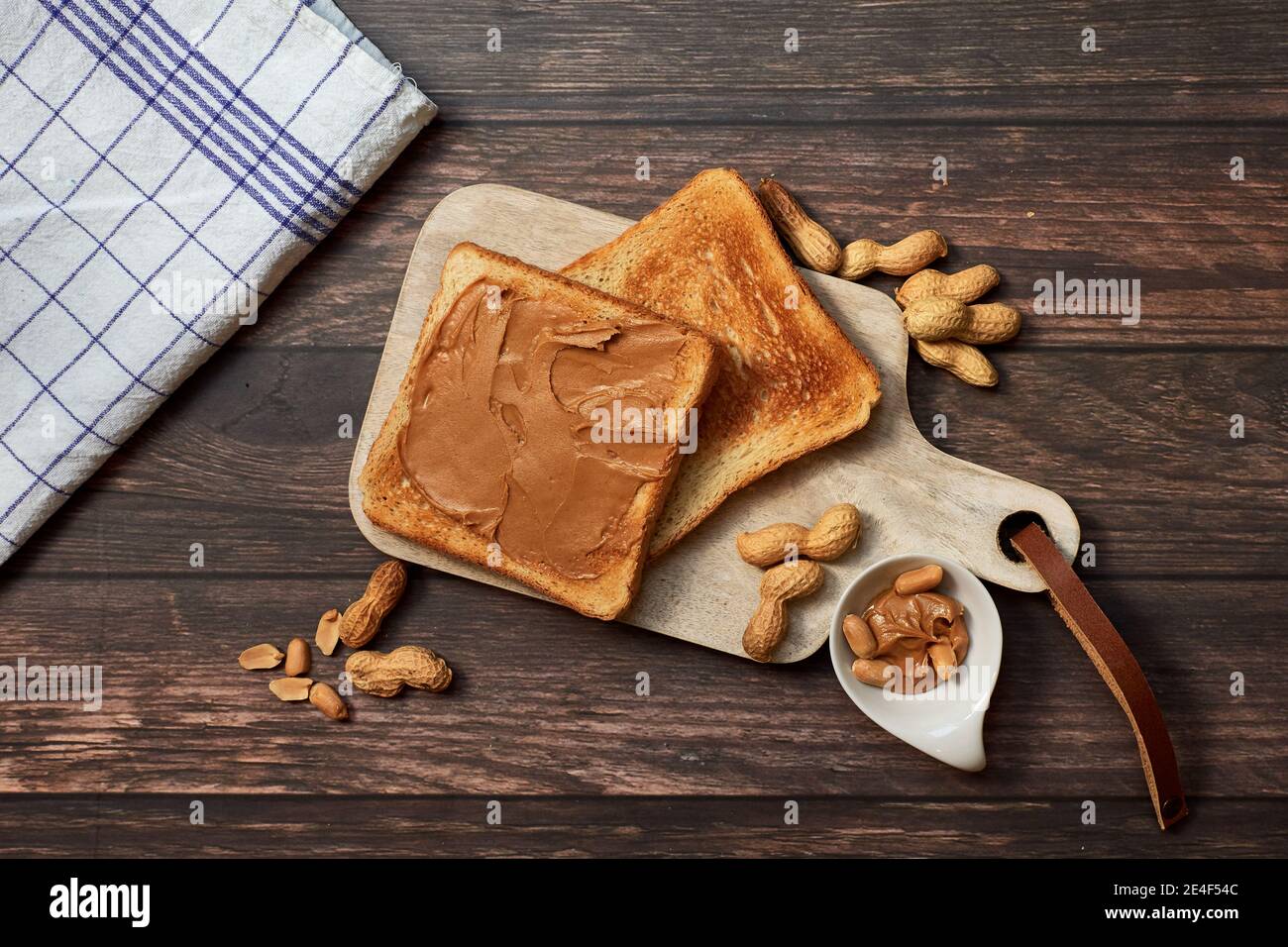 Colazione dolce con pane tostato al burro di arachidi e arachidi su A. tagliere di legno Foto Stock