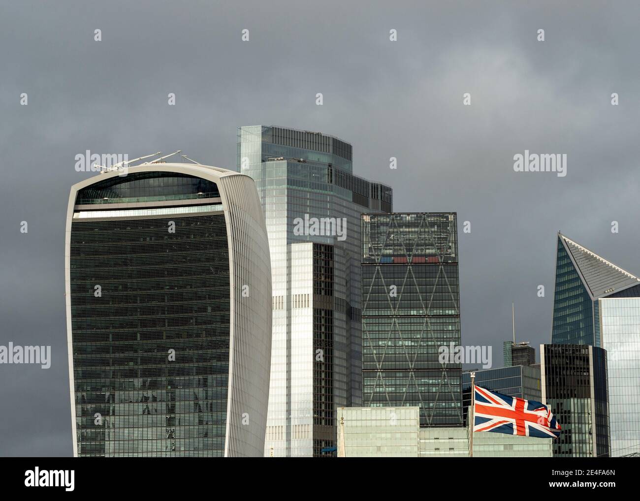 Edifici di grattacieli in vetro dello skyline della città di Londra, il quartiere finanziario di Square Mile e la bandiera di Union Jack che volano sullo sfondo del cielo nuvoloso, Regno Unito Foto Stock