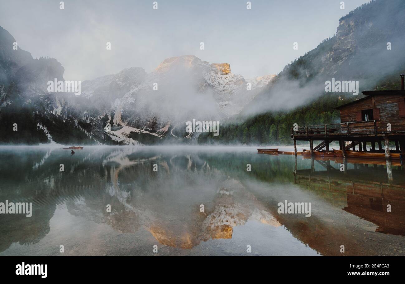 Incantevole vista di un lago circondato da montagne su un nebbia Foto Stock