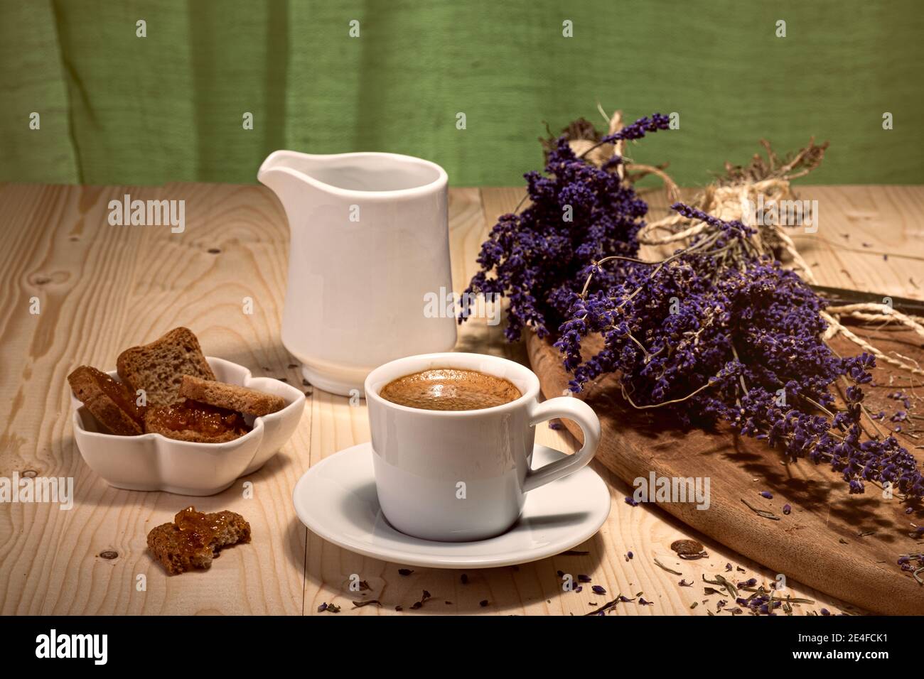 tazza bianca di caffè, in contrasto con lo sfondo verde e il colore viola dei rami secchi di lavanda Foto Stock