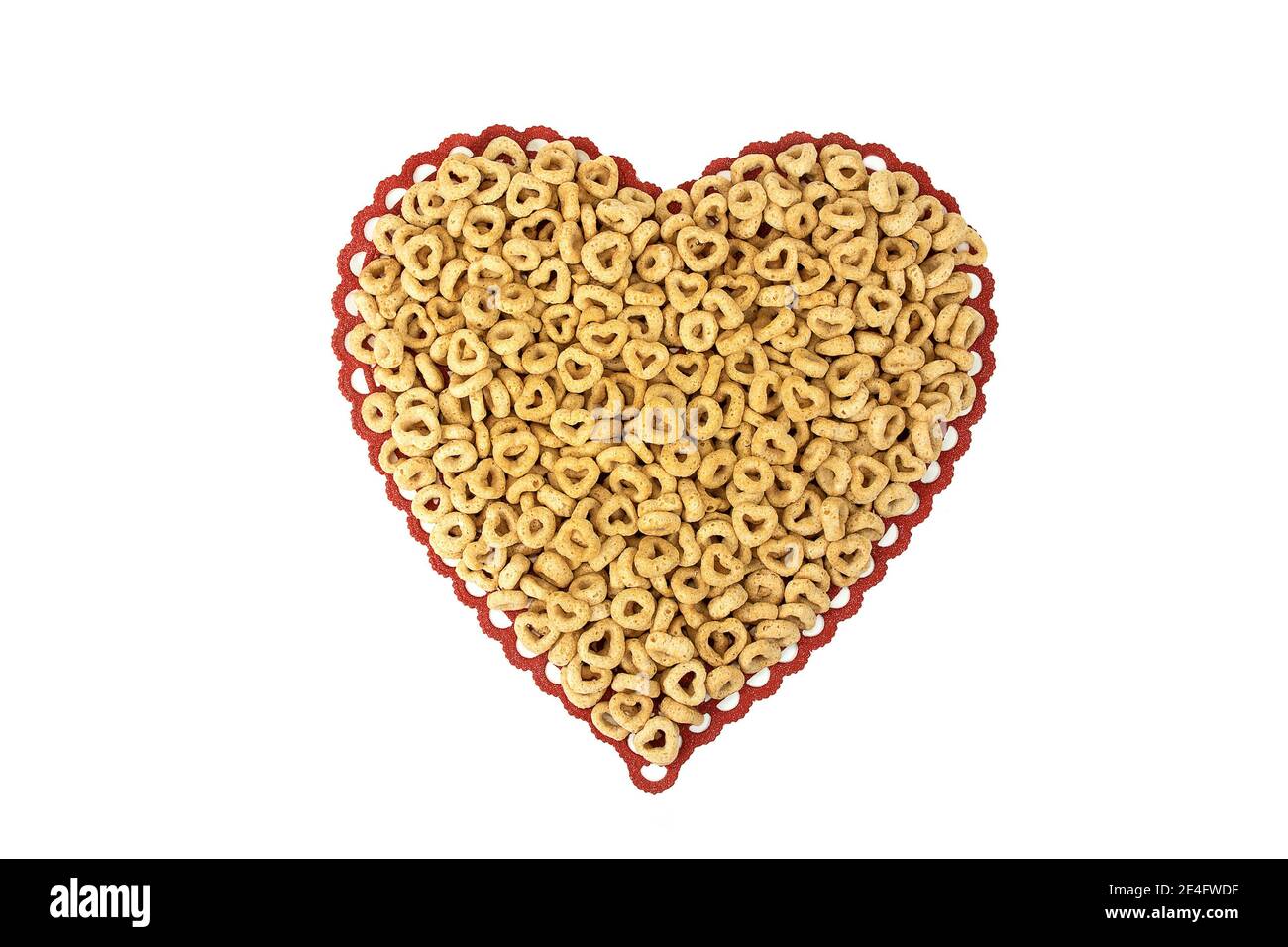 primo piano di cereali per la colazione con cerchi e cuori su rosso merletto cuore isolato doily su bianco Foto Stock